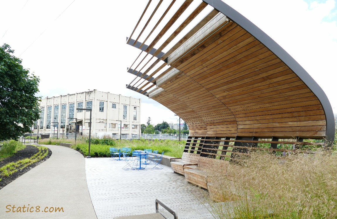 covered benches along the path with a large building in the background