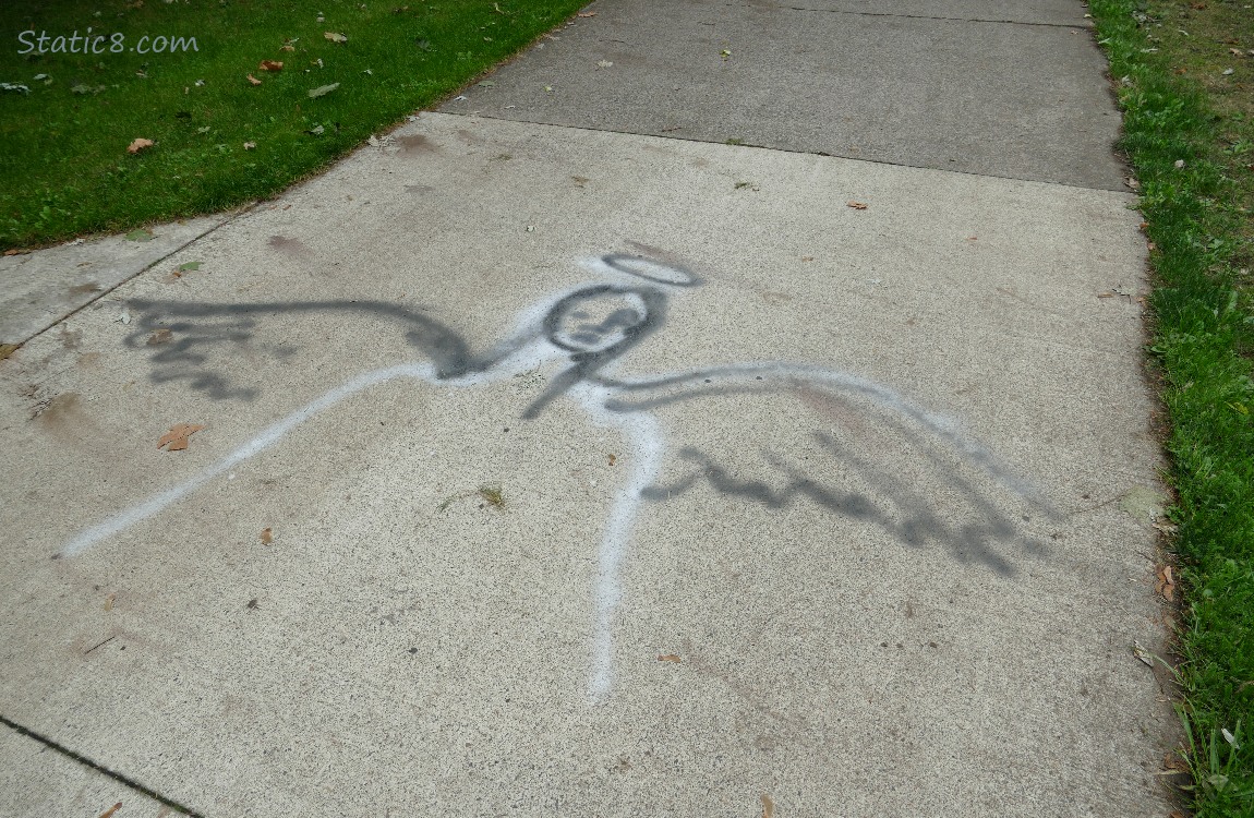 Angel graffiti on the path in black and white paint