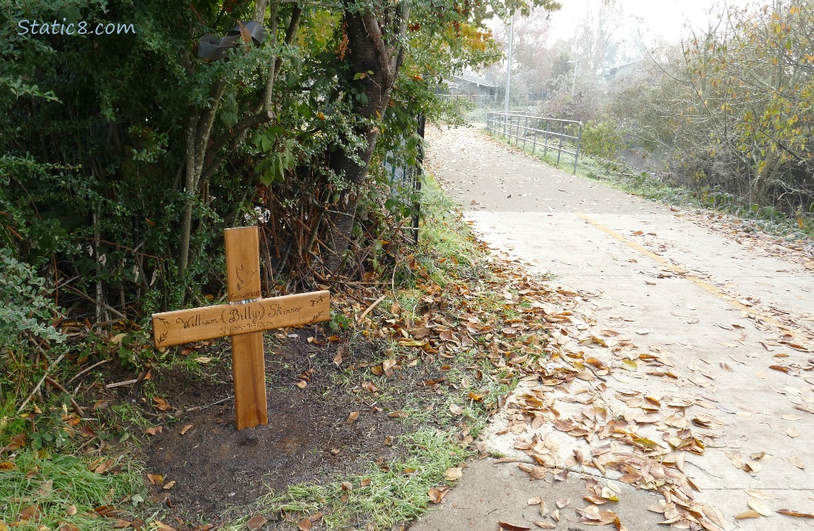 Wood cross next to the bike path, engraved