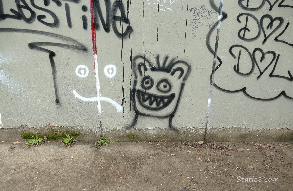 Graffiti on a wall of a smiling monster with sharp teeth
