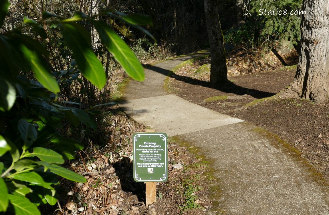 Sign next to a paved trail leading down into the darkness