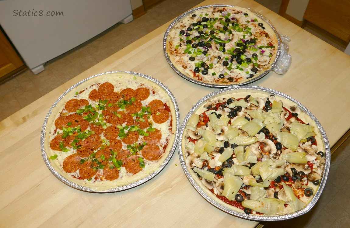 Three pizzas on a butcher block counter