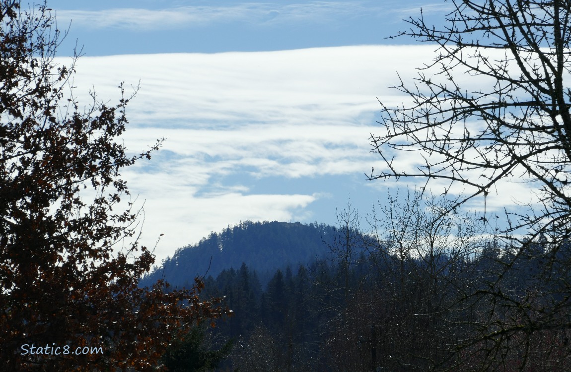 Thin clouds, then blue sky over the hill in the distance