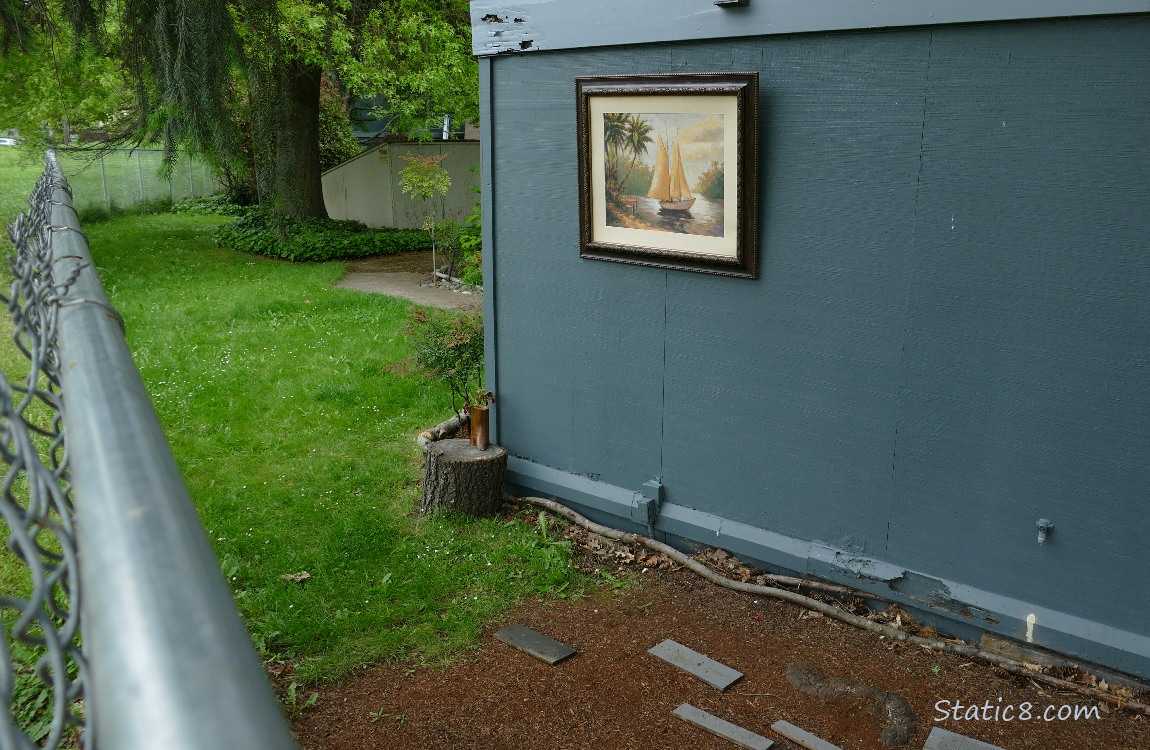 Painting hung on a building past a chain link fence