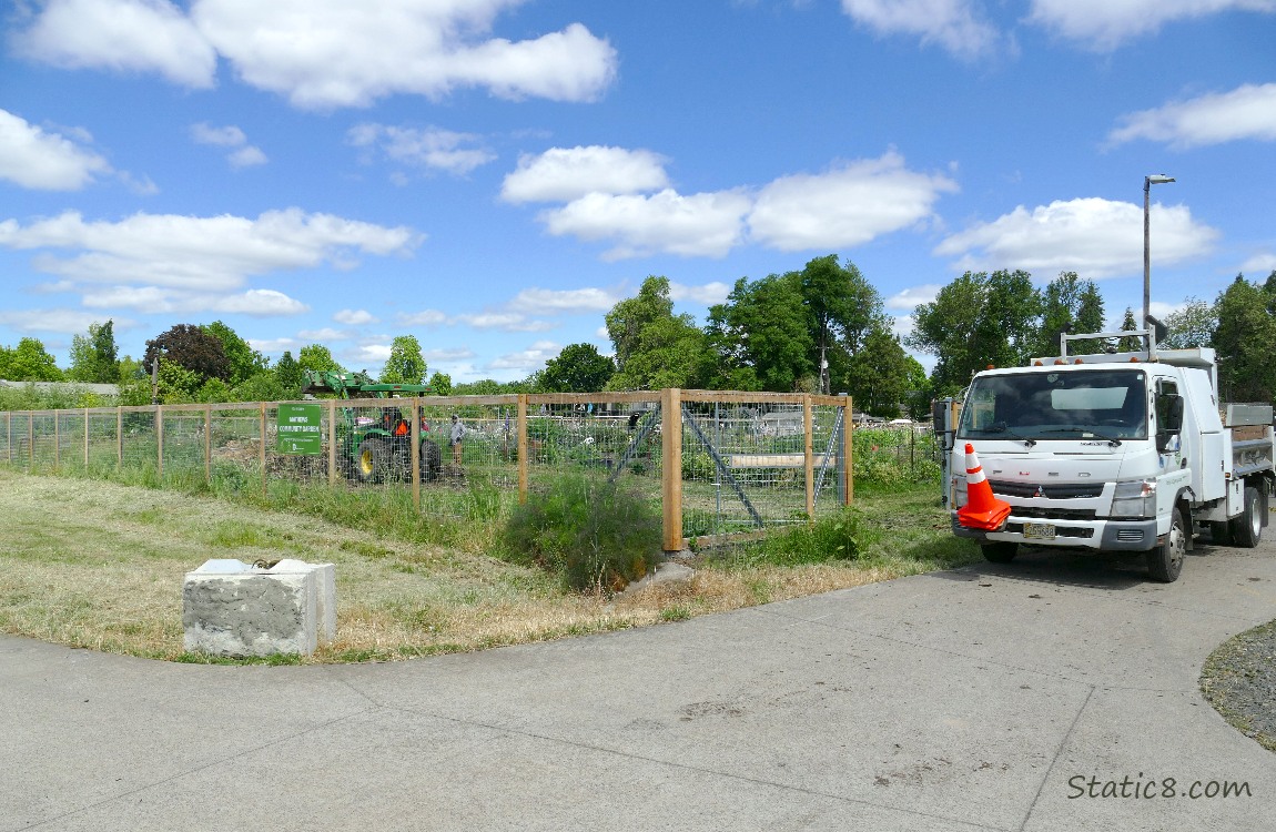 Small dump truck next to the fenced Community Garden