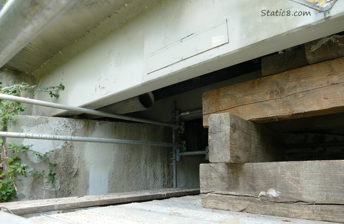 Looking past rigging under a bridge at an open pipe