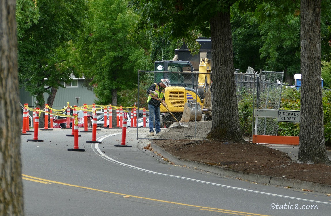 construction guy working on a street, machinery behind him